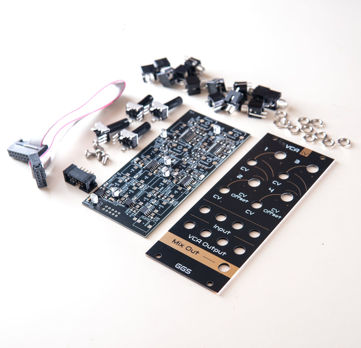 Quad VCA module for eurorack modular synth called VCA IV. White background angled photo of complete DIY kit displaying components such as potentiometers, jack sockets with SMD assembled PCB and Gold plated Front panel PCB art. GGS logo at the bottom.