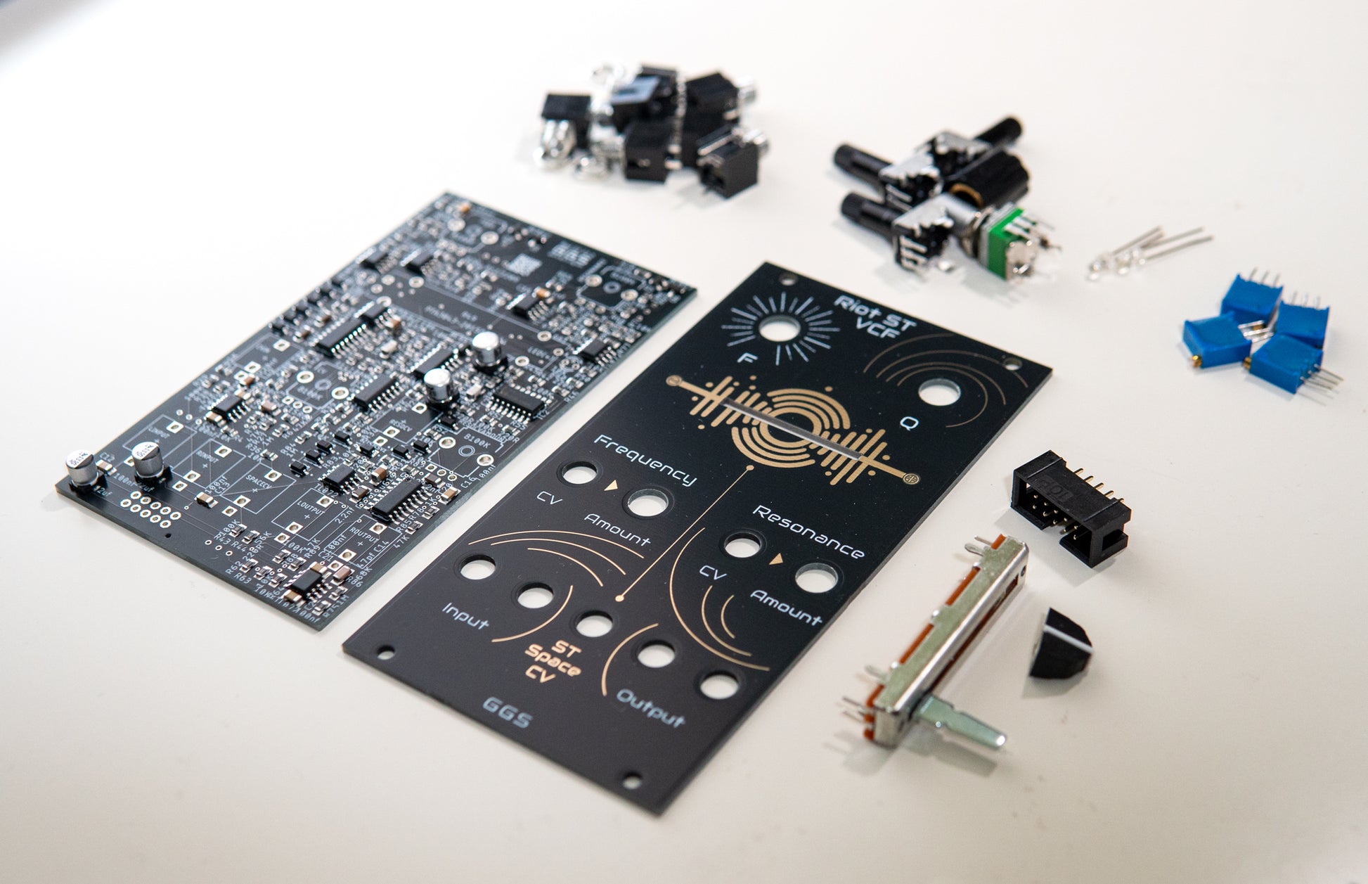 Riot ST VCF - Stereo Low Pass Filter for Eurorack modular synth. Full DIY kit. PCB, front panel and components visible. SMD and THT components such as jack sockets, potentiometers and filter. Photo with an angle.