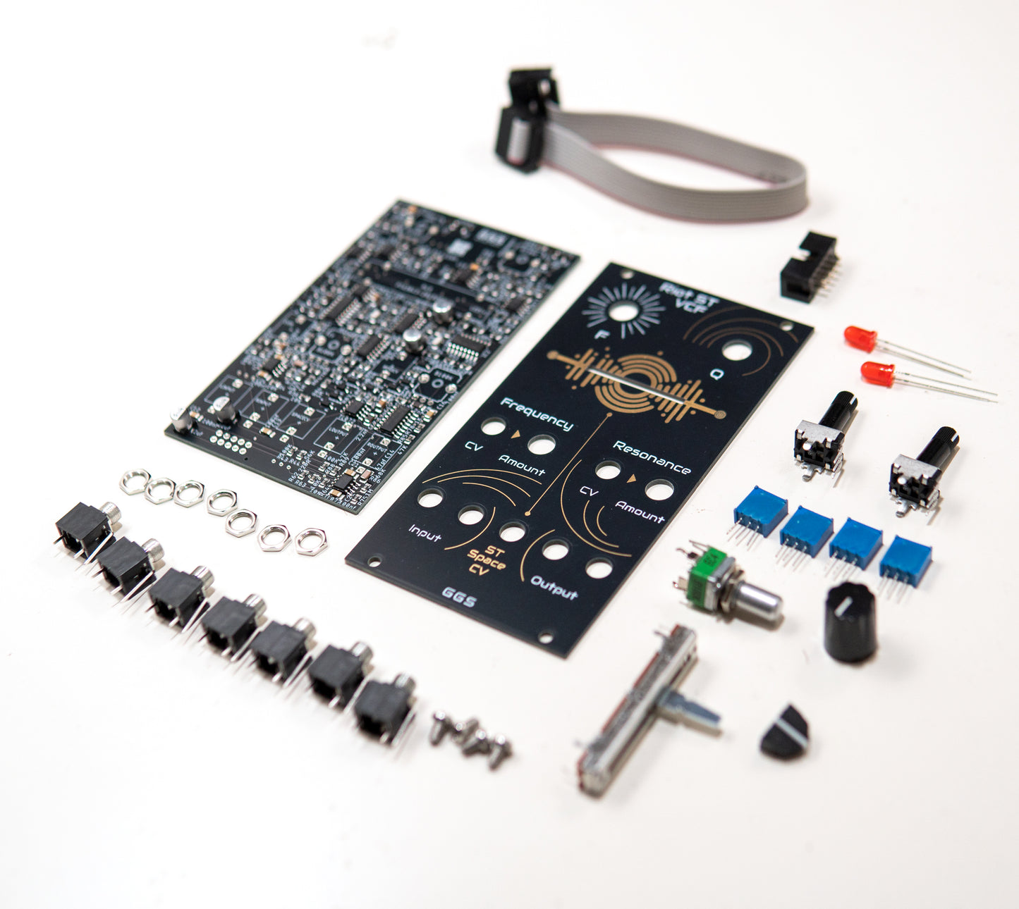 Angled photo of Riot ST VCF Full DIY Kit. Factory assembled SMD PCB and Front Panel surrounded  by all the THT components needed for this eurorack stereo filter module.
